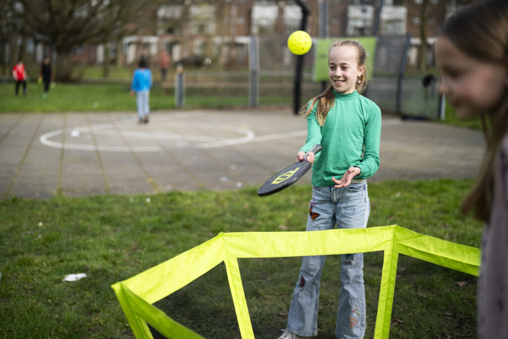 Jong meisje dat een balletje in de korf probeert te mikken